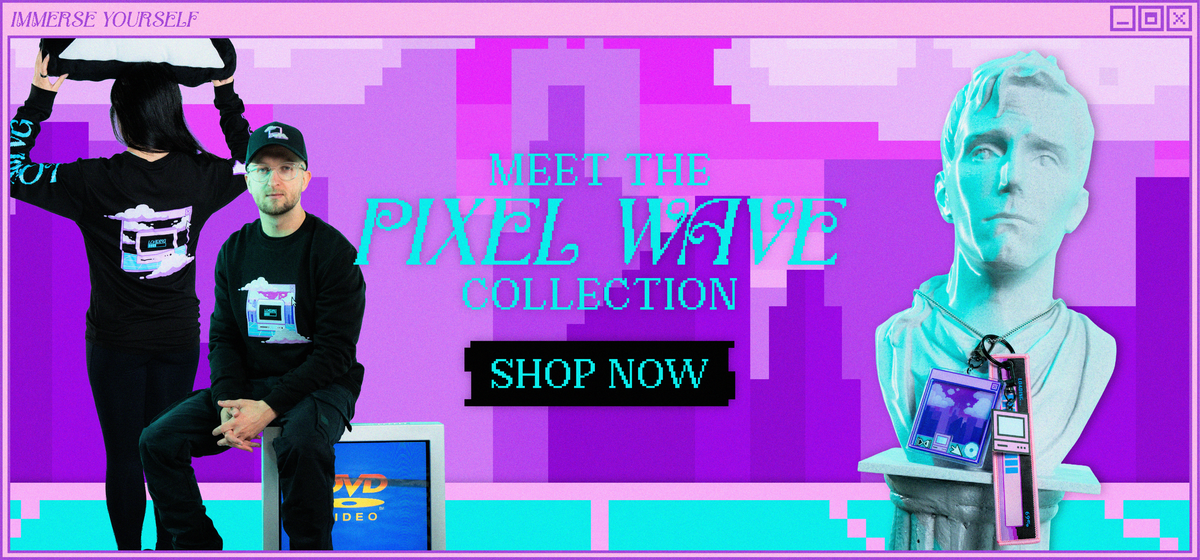 Pixel Wave Collection banner in a pink and purple retro computer window. On the left, two models wear black long-sleeve shirts with a pastel pixel-art computer and cloud graphic. One also wears a black cap with a matching graphic and sits on an old CRT monitor showing a DVD logo. On the right, a white marble bust wears a necklace with a pixel-art window keychain and a computer-shaped strap keychain. The text reads “Meet the Pixel Wave Collection – Shop Now.”